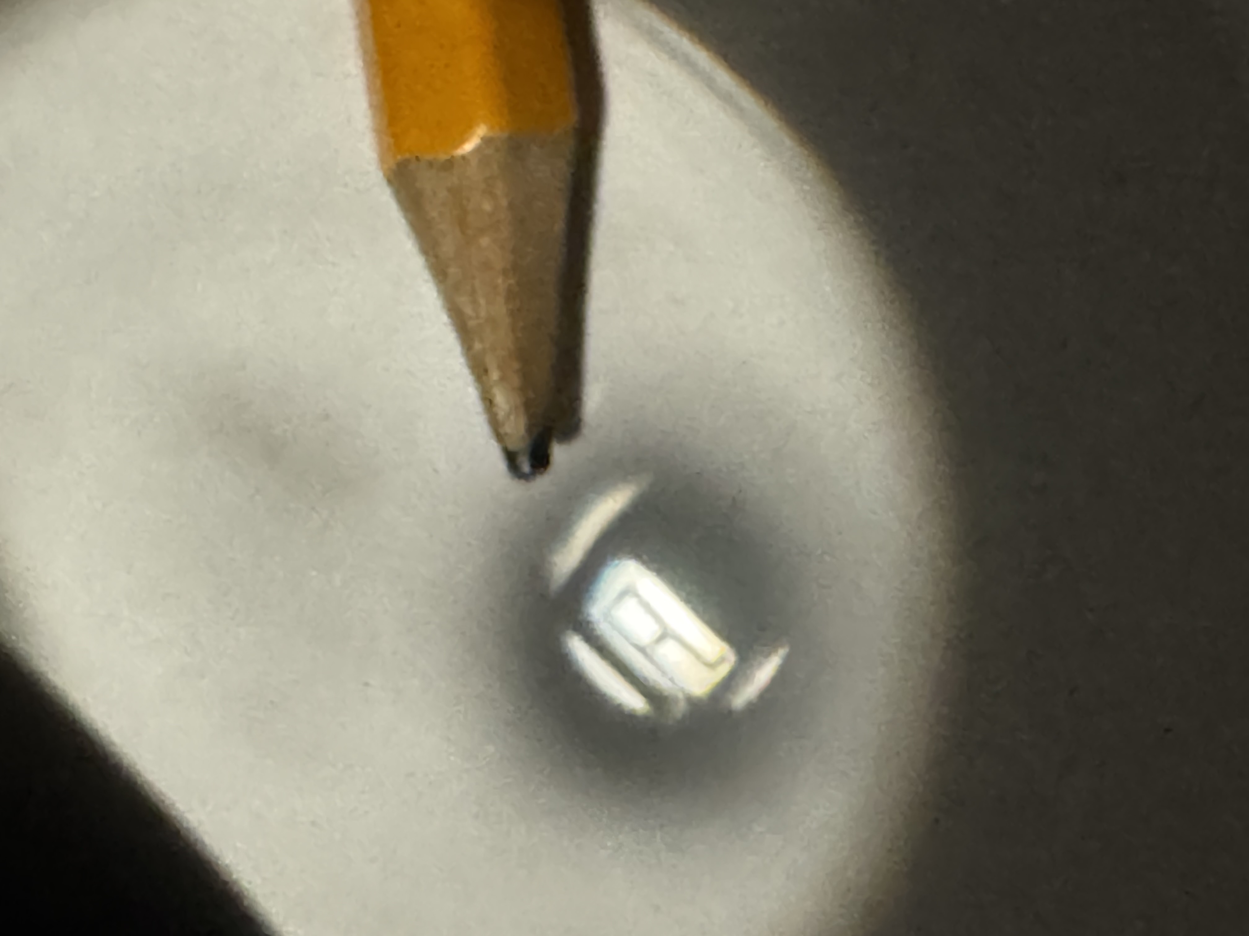 A tiny projected letter A on white paper beside the tip of a pencil